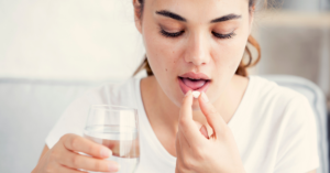 Woman taking Librium, with the pill in one hand and a glass of water in the other.