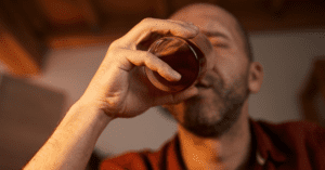 Man taking a drink of alcohol form a glass.