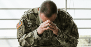 A distressed veteran in uniform sits alone.