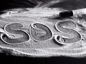 S.O.S. is spelled in a mess of powder or cocaine. There is a needle holding liquid next to the words.
