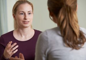 two people stand in front of each other and discuss therapy programs