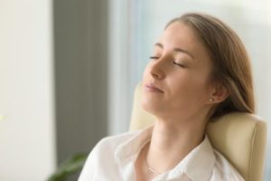 a woman leans back in a chair and meditates to represent a holistic therapy program