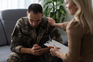 a veteran in fatigues is comforted by an intake specialist to show veterans in addiction recovery