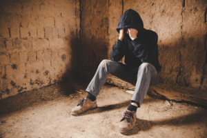 a man in a hoodie leans against a basement to show bipolar symptoms in men