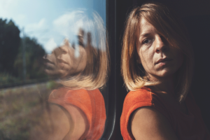 a woman looks sad out of a window to show depression symptoms in women