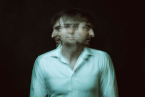 a person looking at the camera with two faces transposed over his, showing what is DMT