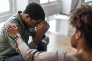 Man cries as his peer from group therapy offers him a gesture of peer support