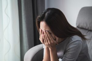 Woman cries into her hands as she thinks about her childhood trauma and addiction issues