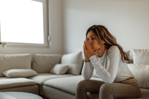 Woman sits on couch as she begins to recognize her reaction as a trauma response