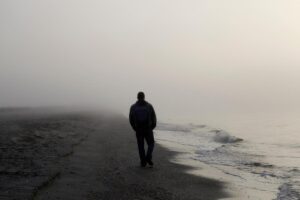 Man walks on the beach alone, as he struggles with both addiction and loneliness