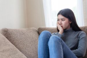 Woman sits on couch and ponders dependence vs addiction